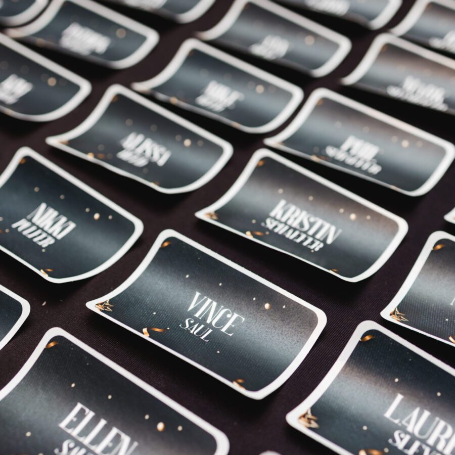 Rows of black name tags with white text are arranged on a dark surface, each displaying different names and surnames.