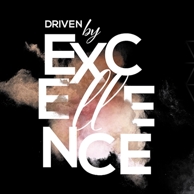 White text on a black background reads "Driven by Excellence" with a cloud of colored powder behind the word Excellence.